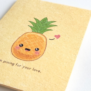 Pode incluir: Um abacaxi amarelo com um rosto bonito e um coração vermelho acima dele. O texto "I'm pining for your love." está escrito abaixo do abacaxi.