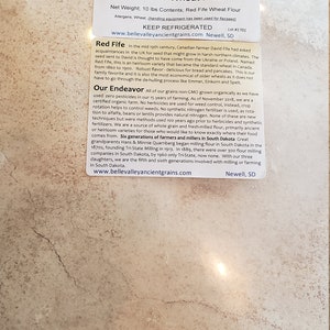 May include: A 10-pound bag of Belle Valley Ancient Grains Red Fife Wheat Flour. The bag is white with a brown label that has a picture of wheat stalks and the text "Belle Valley Ancient Grains Red Fife Wheat Flour". The label also includes information about the product, including the net weight, contents, allergens, and instructions to keep refrigerated. The label also includes the website address www.bellevalleyancientgrains.com and the location Newell, SD.