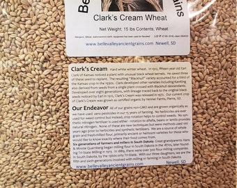 Könnte beinhalten: Nahaufnahme einer Tüte Clark's Cream Wheat, einem harten weißen Winterweizen. Die Tüte ist mit der Website und den Kontaktdaten des Unternehmens beschriftet. Der Weizen ist biologisch angebaut und nicht gentechnisch verändert. Die Tüte enthält 15 Pfund Weizen.