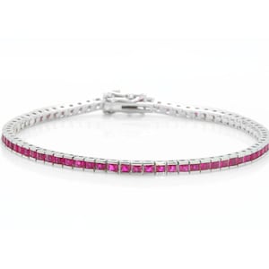 May include: A silver bracelet with a row of square-cut, vibrant pink gemstones. The bracelet has a secure clasp and is set against a white background, showcasing the jewelry's design and color.