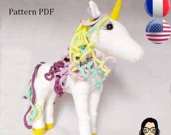 May include: Crocheted unicorn amigurumi toy with a white body, yellow hooves, and a rainbow mane and tail. The unicorn has a yellow horn and brown eyes. The toy is sitting on a white background. Pattern PDF.