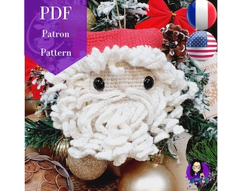 Puede incluir: Patrón de crochet para un adorno de Papá Noel. El adorno es blanco con un gorro rojo y ojos negros. El patrón está disponible en inglés y francés.