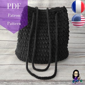 Può includere: Una borsa tote in crochet nero con un design testurizzato e gonfio. La borsa ha due lunghe cinghie ed è realizzata con un filato spesso.