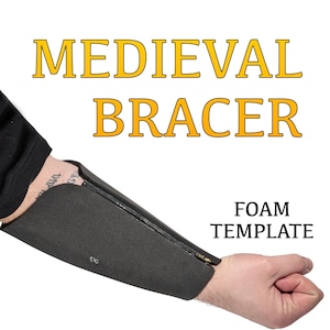 May include: A foam template for a medieval bracer, with a zipper closure. The template is gray and has a black zipper. The text "FOAM TEMPLATE" is printed in white on a black background.