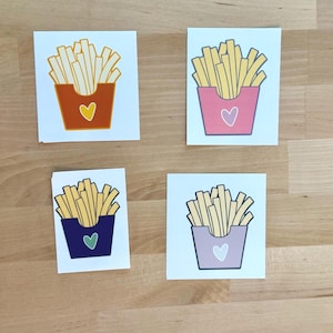 Puede incluir: Cuatro tarjetas cuadradas con ilustraciones de patatas fritas en diferentes recipientes de colores. Cada recipiente tiene forma de corazón. Los recipientes son naranja, rosa, azul marino y lavanda. Las patatas fritas son amarillas.