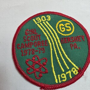 May include: A round Girl Scout Camporee patch with a green background and red border. The patch features yellow and red embroidered details, including the text "Girl Scout Camporee 1978-79 Hershey PA." and the Girl Scout logo.