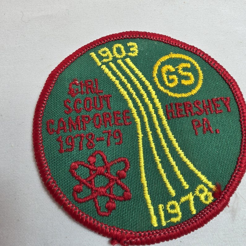 May include: A round Girl Scout Camporee patch with a green background and red border. The patch features yellow and red embroidered details, including the text "Girl Scout Camporee 1978-79 Hershey PA." and the Girl Scout logo.