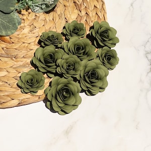 May include: A collection of ten green paper flowers arranged in a cluster. The flowers are made of paper and have a realistic appearance.