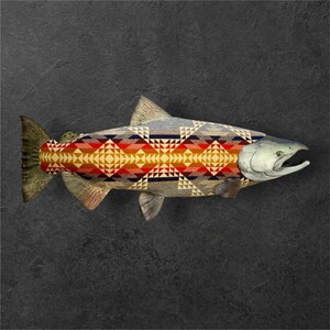 May include: A salmon fish with a colorful geometric pattern on its body. The pattern is in shades of red, yellow, blue, and white. The fish is lying on a dark gray background.