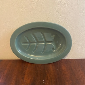 May include: A light blue oval ceramic serving dish with a raised fish bone design.