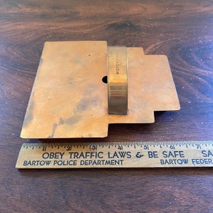 May include: A vintage metal cookie cutter in the shape of a house with a handle. The cookie cutter is made of brass and has a worn, aged look. The words "OCCASION" are engraved on the handle.