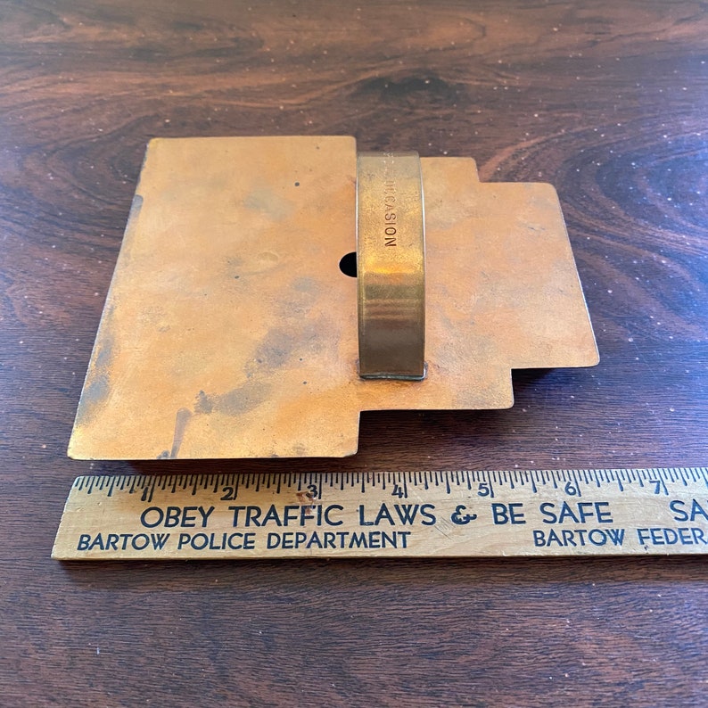 May include: A vintage metal cookie cutter in the shape of a house with a handle. The cookie cutter is made of brass and has a worn, aged look. The words "OCCASION" are engraved on the handle.