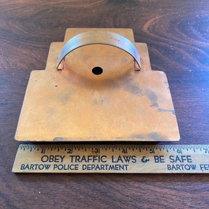 May include: A vintage metal cookie cutter shaped like a house with a handle. The cookie cutter is made of copper and has a dark patina. The handle is attached to the top of the house and has the words "Made in USA" on it. The cookie cutter is about 5 inches tall and 4 inches wide.