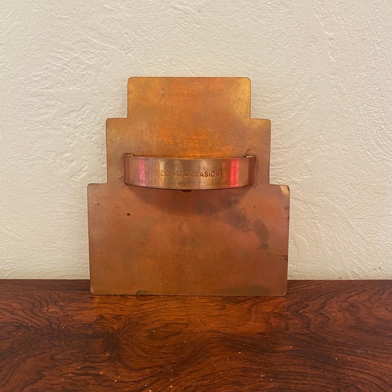 May include: A copper-colored metal cookie cutter shaped like a tiered cake with the words "Special Occasion" engraved on the handle.