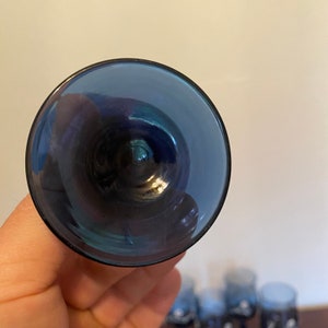 May include: The bottom of a blue glass goblet. The glass is clear and has a slight iridescent sheen.