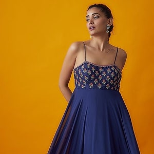 Featuring a navy blue strappy dress in georgette base with floral boota embroidery.