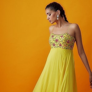 Met een gele strappy jurk in georgette-basis met borduursel.