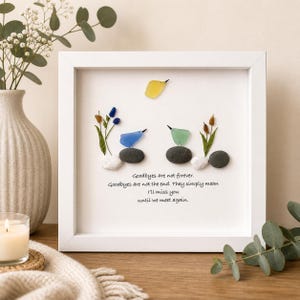 May include: A framed artwork featuring colorful glass birds and plants on a white background. The artwork includes the text "Goodbyes are not forever. Goodbyes are not the end. They simply mean I'll miss you until we meet again."