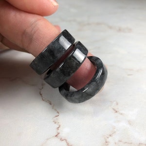 May include: Three black jade rings stacked on top of each other. The rings are smooth and polished.