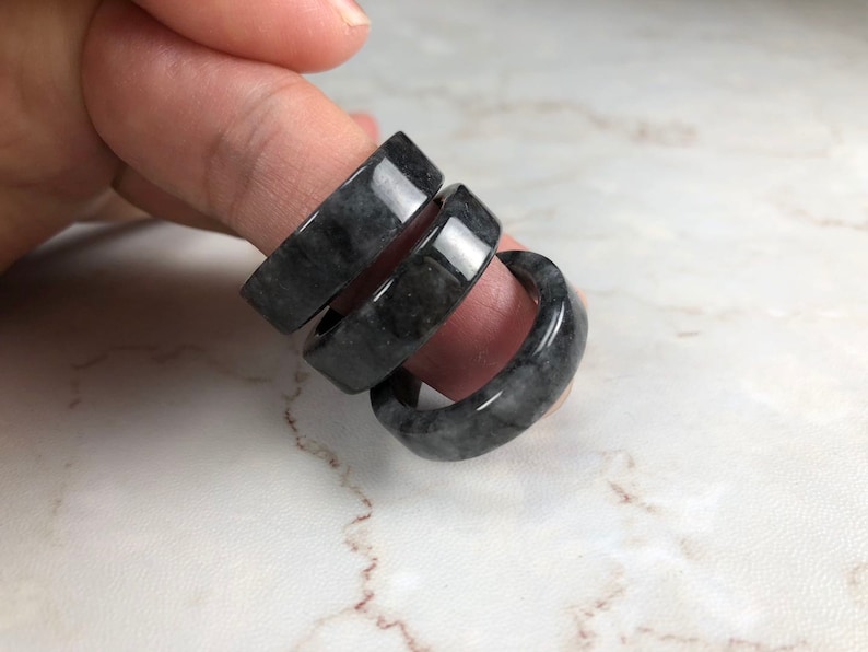 May include: Three black jade rings stacked on top of each other. The rings are smooth and polished.