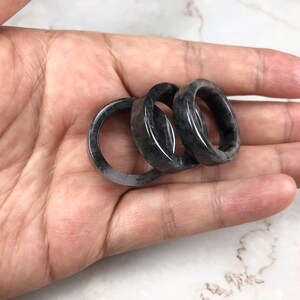 May include: Three black and gray stone rings stacked on top of each other.