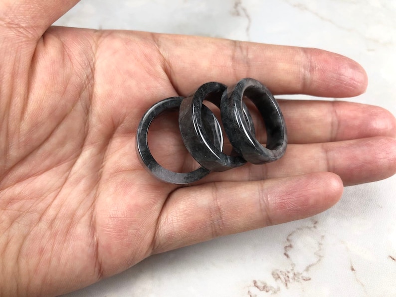 May include: Three black and gray stone rings stacked on top of each other.