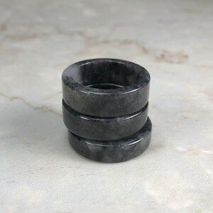 May include: Three stacked black and gray jade rings. The rings are smooth and polished.
