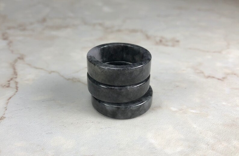 May include: Three stacked black and gray jade rings. The rings are smooth and polished.