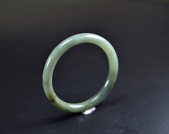 May include: A jade green bangle bracelet with a smooth, polished finish.