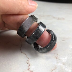 May include: Three stacked rings made of black and gray jade. The rings are smooth and polished.