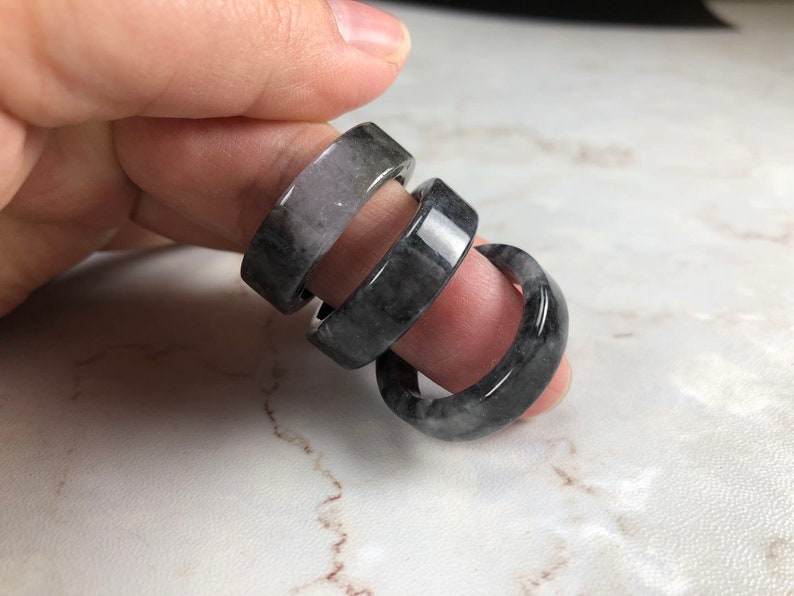 May include: Three stacked rings made of black and gray jade. The rings are smooth and polished.