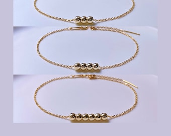Peut inclure: Trois bracelets en or de différentes longueurs, chacun avec une rangée de perles rondes en or.
