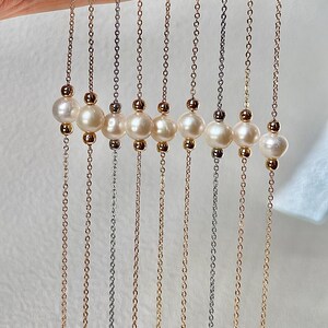 May include: A set of nine delicate necklaces featuring a chain with a row of five white pearls. The chains are in different metal finishes, including gold, silver, and rose gold.