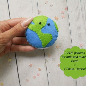 May include: A felt Earth toy with a smiling face and green and blue colors. The toy is being held in a hand. The image also includes text that says "2 PDF patterns for little and middle Earth + 1 Photo Tutorial".
