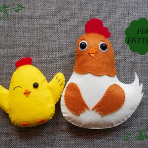 K&ouml;nnte beinhalten: Ein PDF-Muster zum N&auml;hen von zwei Filz-H&uuml;hnern. Ein Huhn ist gelb mit einem roten Kamm und das andere ist braun und wei&szlig; mit einem roten Kamm. Das Muster enth&auml;lt Anweisungen zum Herstellen der H&uuml;hner.