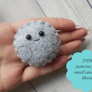 May include: A gray felt moon with a smiling face and black eyes. The moon is being held in a hand. The text "2 PDF patterns for small and big Moon" is in a blue cloud shape.