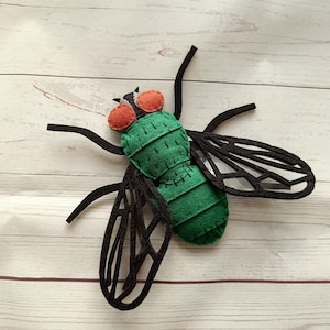 May include: A green felt fly with black felt wings and red felt eyes. The fly is a handmade toy.