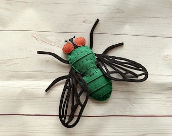 May include: A green felt fly with black felt wings and red felt eyes. The fly is a handmade toy.