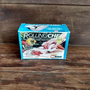 May include: A blue box for the "Rolling Chef" hand-held food processor. The box features the product name in large white letters, along with a picture of the product in use. The box also lists features like easy cleaning and stainless steel blades.