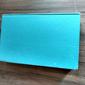 K&ouml;nnte beinhalten: Ein t&uuml;rkisfarbenes Hardcover-Buch mit einem glatten, strukturierten Einband.