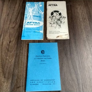 May include: Three blue and white pamphlets with the text "AFTRA" and "American Federation of Television and Radio Artists" on the covers. The pamphlets are titled "Guide Book", "Talent & Rate Guide", and "Articles of Agreement and Constitution".