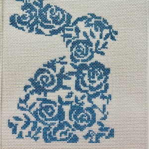 May include: Blue floral embroidery design on a white canvas with the word "MEIRU" in pink lettering at the bottom.