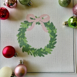 May include: A green wreath with a pink bow on a white canvas background. The wreath is surrounded by various coloured ornaments.