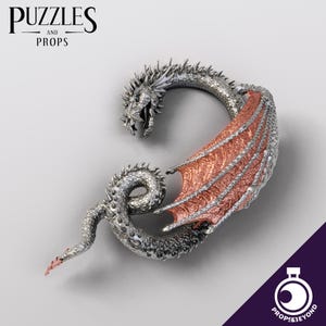 May include: A silver dragon with copper wings curled into a circle. The dragon's head is facing forward with its mouth open. The dragon is a decorative piece.