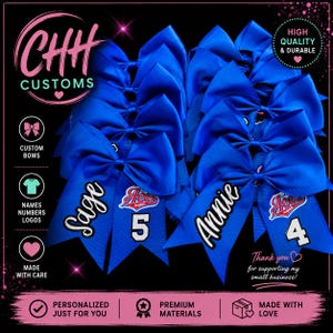 May include: A collection of royal blue hair bows featuring personalized white lettering with the names Sage and Annie, alongside the numbers 5 and 4, and team logos. The bows are arranged in a group against a black background with text.
