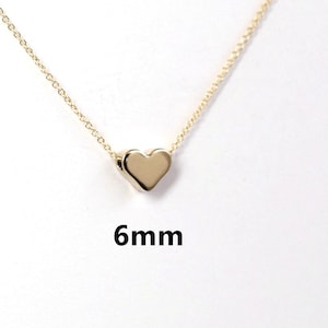 May include: A delicate gold chain necklace with a small, solid gold heart pendant. The heart is 6mm in size.