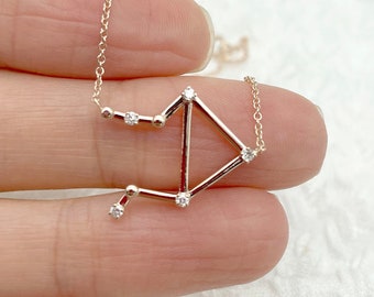 May include: A delicate gold necklace with a constellation pendant featuring small sparkling diamonds. The pendant is shaped like the constellation Libra.