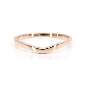 May include: A simple, curved, rose gold band ring.