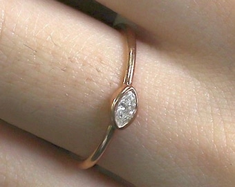 May include: A delicate rose gold ring with a single marquise-shaped diamond set in the center.