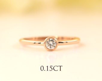 May include: A simple rose gold band ring with a single round diamond set in a bezel setting. The diamond is 0.15 carats.